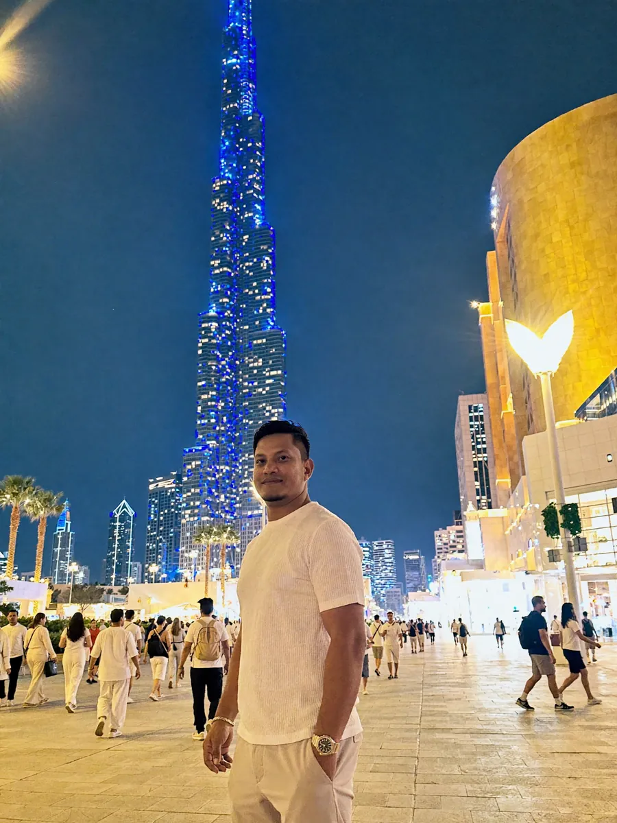 Habib in white in front of Burj Khalifa lit up at night